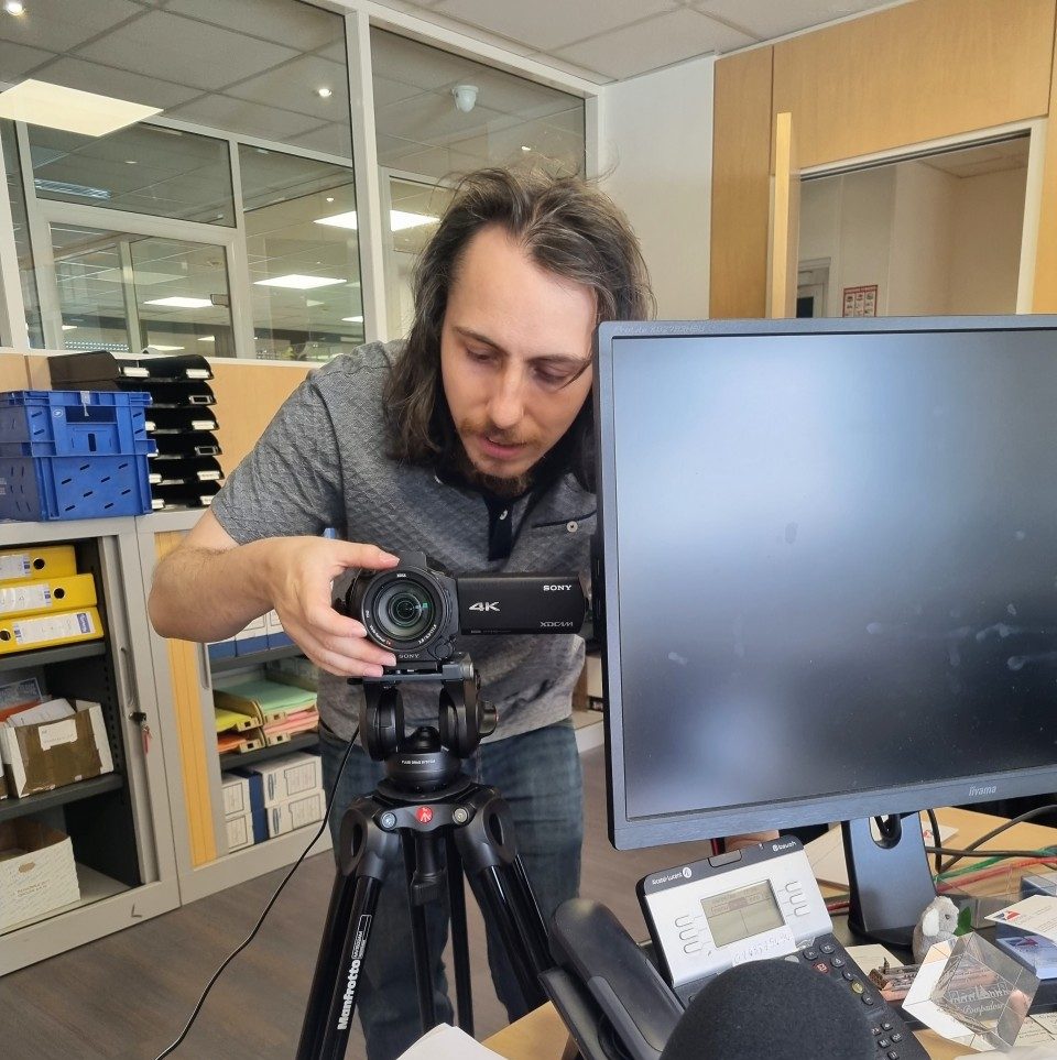 Florian les mains sur la caméra dans un bureau de la Centrale Canine